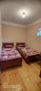 two beds in a room with wooden floors at Guest House Sabauri in Kazbegi