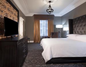 Cette chambre comprend un lit et une télévision à écran plat. dans l'établissement Le Pavillon New Orleans, à La Nouvelle-Orléans