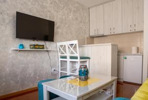 eine Küche mit einem Tisch und einem TV an der Wand in der Unterkunft Central Apartment in Niksic in Nikšić