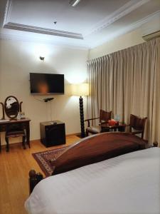 a bedroom with a bed and a desk and a television at Al Khariss Hotel in Doha