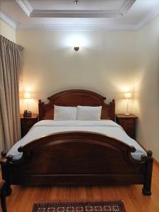 a bedroom with a large wooden bed with two lamps at Al Khariss Hotel in Doha