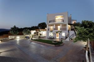 a large white house with a courtyard at night at Marakis Villas in Kavrokhórion