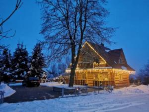 una cabaña de madera cubierta de luces de Navidad en la nieve en Vila Vilinka & Vila Native Vilinija resort Village, en Podčetrtek