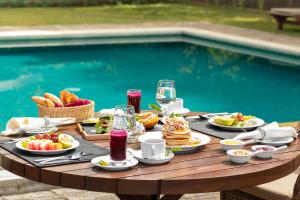 una mesa con comida y bebida junto a una piscina en The Lavender House by Reveal en Kandy