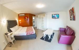 ein Hotelzimmer mit einem Bett, einer Couch und einem Tisch in der Unterkunft Détente Hôtel in Abidjan