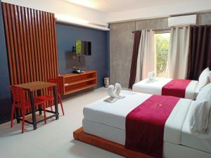 a bedroom with two beds and a table and a desk at La Gensol Plaza Hotel in Mamburao