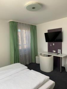 ein Hotelzimmer mit einem Bett und einem Schreibtisch mit einem TV in der Unterkunft Eisberg Hotel Schwanen in Lahr
