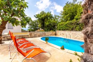 a swimming pool with two lounge chairs next to a swimming pool at Apartment in Njivice with sea view, balcony, air conditioning, WiFi (4930-2) in Njivice