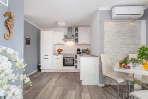 een keuken met witte apparatuur en een tafel met stoelen bij Apartment in Njivice with sea view, balcony, air conditioning, WiFi (4930-2) in Njivice