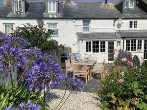 a house with a table and chairs and purple flowers at Beehive Cottage in Port Isaac