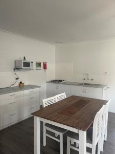 a kitchen with a wooden table and white cabinets at Busselton Jetty Chalets in Busselton