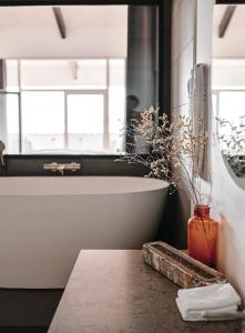 ein Badezimmer mit einer Badewanne und einer Vase auf einem Tisch in der Unterkunft Langhoff & Juul Boutique Hotel og Restaurant in Ebeltoft