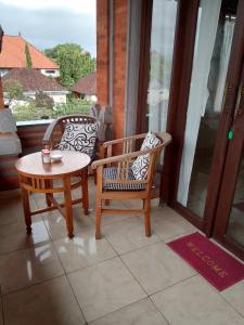 een veranda met 2 stoelen, een tafel en een raam bij Tunjung Guest House in Ubud