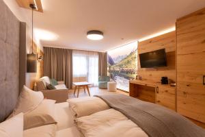 ein Schlafzimmer mit einem Bett und einem TV in einem Zimmer in der Unterkunft Hotel Mittagskogel Pitztal in Sankt Leonhard im Pitztal