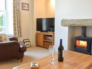 a living room with a wine bottle and a glass on a table at North Road Cottage in Hackforth