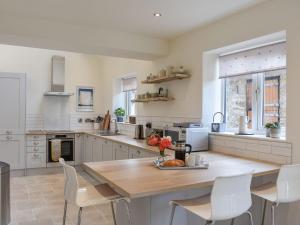 a kitchen with a wooden table and white chairs at North Road Cottage in Hackforth