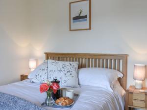 a bed with a tray of bread and flowers on it at North Road Cottage in Hackforth