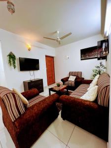 a living room with two couches and a flat screen tv at Cozy 2BHK condo surrounded with greenery. in Mangalore