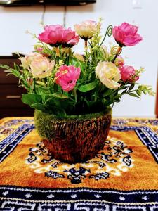 een vaas gevuld met bloemen zittend op een tafel bij Cozy 2BHK condo surrounded with greenery. in Mangalore