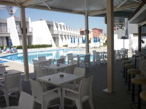 un patio con mesas y sillas y una piscina en Penelope Beach Hotel Apts en Protaras