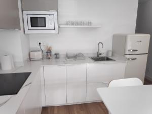 cocina blanca con fregadero y microondas en Apartamentos CANDEA, en Lugo