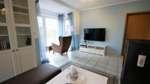 a living room with a couch and a television at Ferienwohnungen Huus Diekenblick in Butjadingen