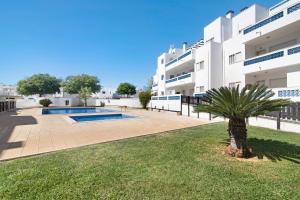 a large white building with a palm tree in front of it at Santa Luzia Apartment Sl016 in Santa Luzia