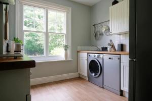 Contemporary 2 Bedroom Flat in Lewes في لويس: مطبخ مع غسالة ملابس ونافذة