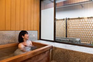 a woman sitting in a bath tub with at Hotel Hagoromo in Shizuoka