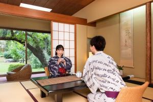 un hombre y una mujer en kimono sentados en una mesa en Hotel Hagoromo, en Shizuoka