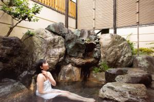 a woman sitting in a pool of water at Hotel Hagoromo in Shizuoka