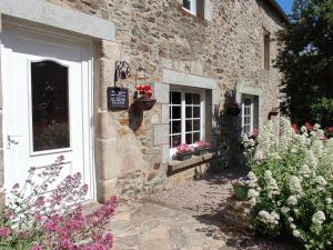 un edificio de piedra con flores delante en Chambres d'Hôtes Au Clos du Lit, en Lamballe