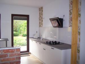 a kitchen with white cabinets and a sink and a window at Ferienwohnungen Jedebrock in Burhave