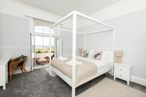 Habitación blanca con cama con dosel y espejo. en SoHot Stays - Sea Views From Every Room, en Westgate on Sea