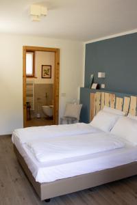 1 dormitorio con 1 cama blanca grande y baño en Storie di bosco, en Villa Lagarina