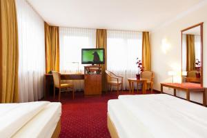 a hotel room with two beds and a table and a television at Hotel am Berliner Platz in Langenfeld