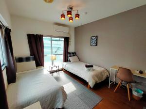 a bedroom with two beds and a desk and a window at Coco Fukuoka Chiyo in Fukuoka