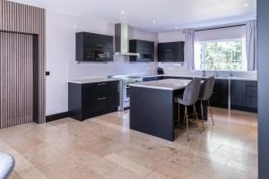 una cocina con armarios negros y una isla con taburetes. en Luxurious 4BD family Retreat in Magherafelt, en Maghera