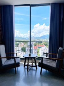 ニャチャンにあるMarilyn Boutique Hotel Nha Trangのテーブルと椅子、大きな窓が備わる客室です。