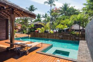 a swimming pool with a wooden deck with a bench next to it at Pousada Villa Maeva Itacare in Itacaré