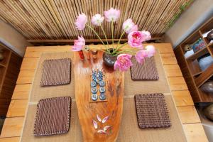 um vaso cheio de flores cor-de-rosa sobre uma mesa em Onsen Villas - Venuestay em Hòa Bình