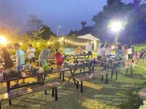 un grupo de personas de pie alrededor de mesas de picnic por la noche en Onsen Villas - Venuestay en Hòa Bình