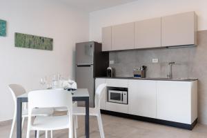 una cucina con armadi bianchi e un tavolo con sedie bianche di Oneweek Gaeta Suites and Apartments a Gaeta