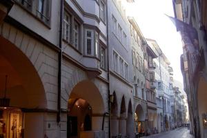 eine Stadtstraße mit Gebäuden und einer Gasse mit Flagge in der Unterkunft Lauben Apartment Bolzano in Bozen