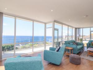 a living room with blue chairs and large windows at Boscregan in Helston