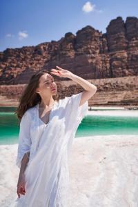 a woman in a white dress standing on a beach at Mövenpick Resort & Spa Dead Sea in Sowayma