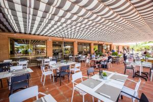 an empty restaurant with white tables and chairs at Camping Vendrell Platja in Comarruga