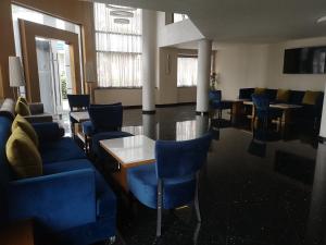 - une salle d'attente avec des tables et des chaises bleues et une télévision dans l'établissement Annakhil Hotel, à Rabat