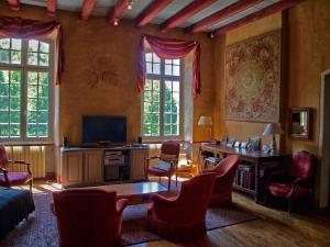 a living room with a tv and a desk and chairs at La Mouline in Labastide-du-Vert