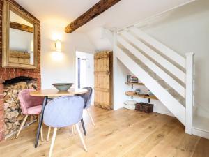 a dining room with a table and chairs and a staircase at Wherry Cottage in Manningtree
